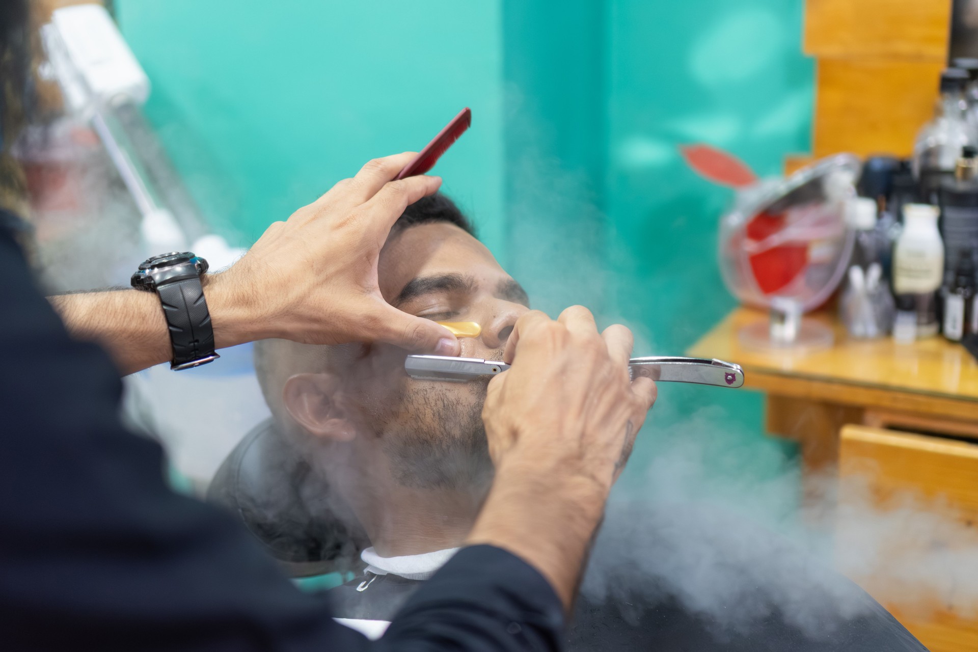 Barber shaving client's beard with a straight razor in a barbershop